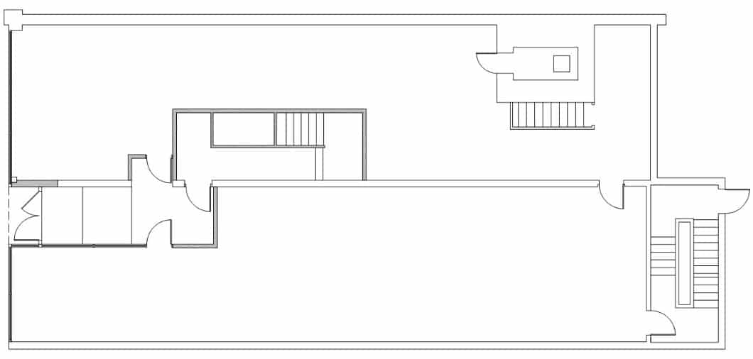 Black and white architectural floor plan illustrating downtown Champaign loft apartments and commercial space, featuring multiple rooms, interior walls, doors, and two staircases on opposite sides of the layout.